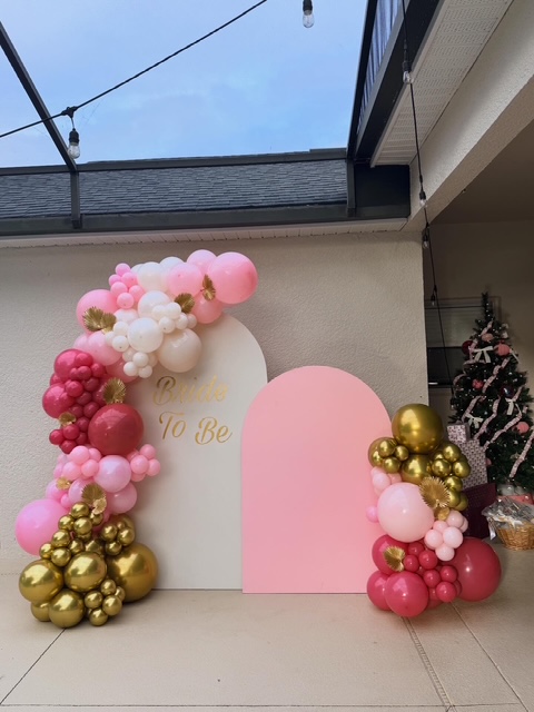 Pink, white, and gold organic balloon garland on arched Bride to Be backdrops